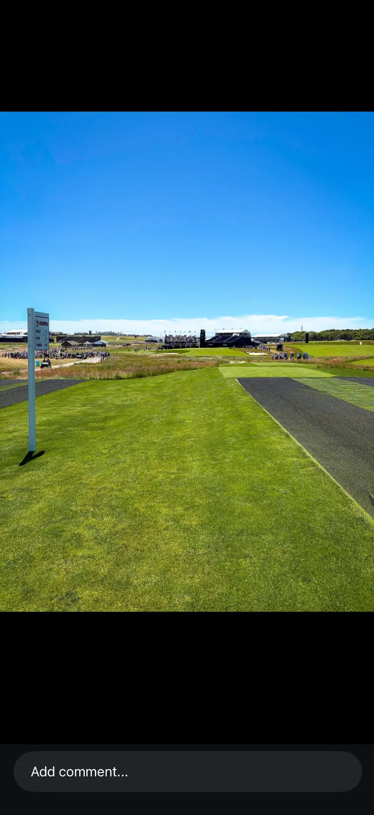 Par-3 championship tee with a US Open branded scoreboard and grandstands in the distance