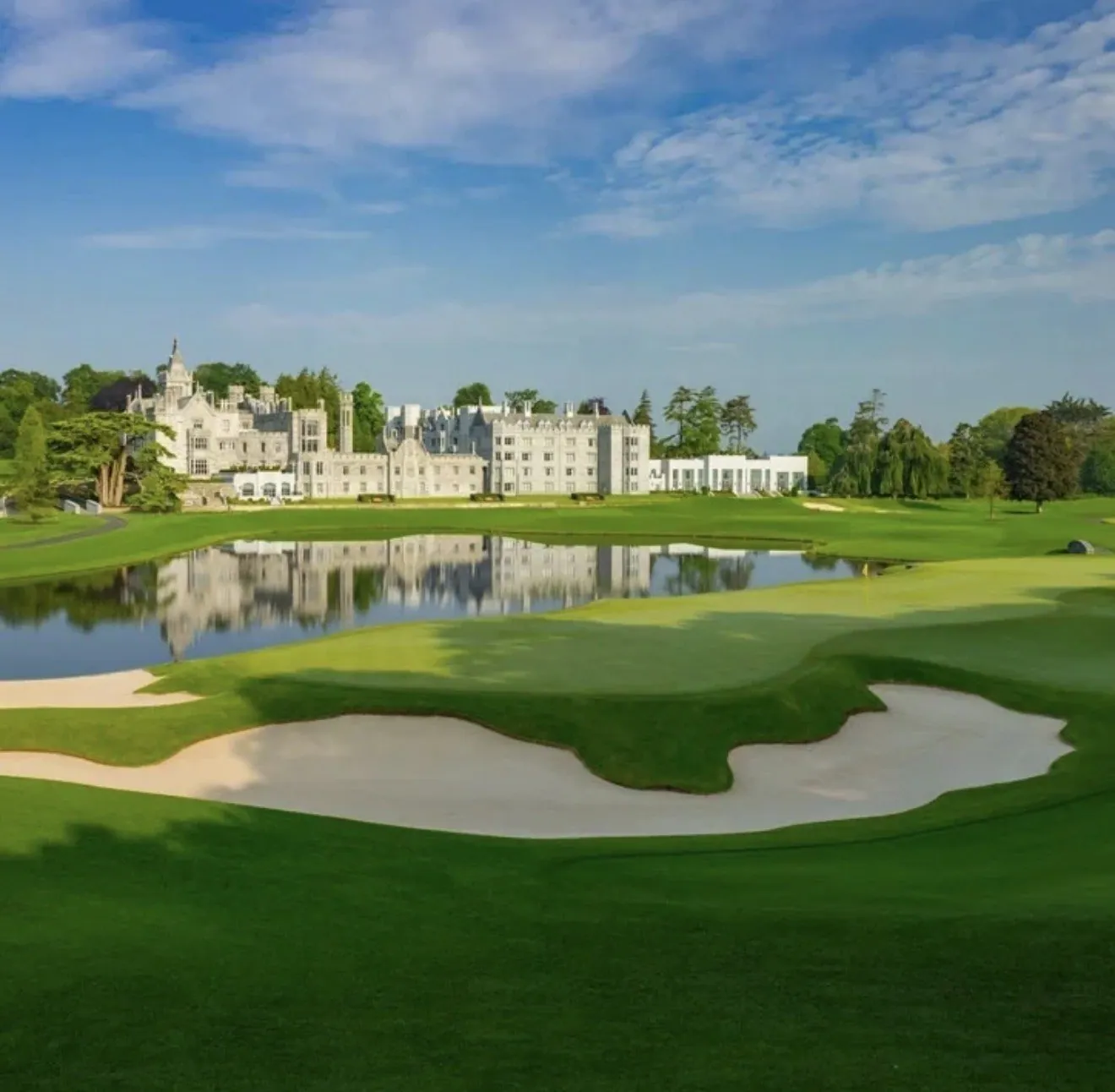 Adare Manor hotel reflected in the lake behind a large white sand bunker and green on the Adare Manor championship golf course, County Limerick, Ireland