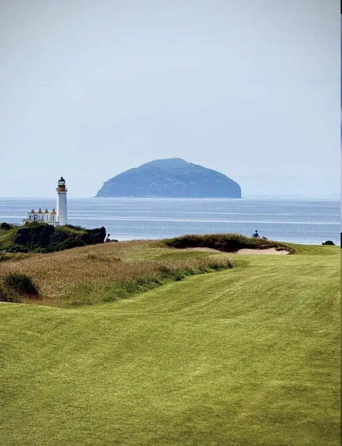 Turnberry lighthouse on the headland with Ailsa Craig rising out of the sea behind the links