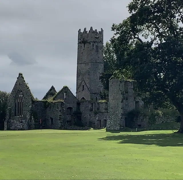 Medieval Franciscan Friary stone ruins and bell tower beside a green fairway at Adare Manor golf course in County Limerick, Ireland