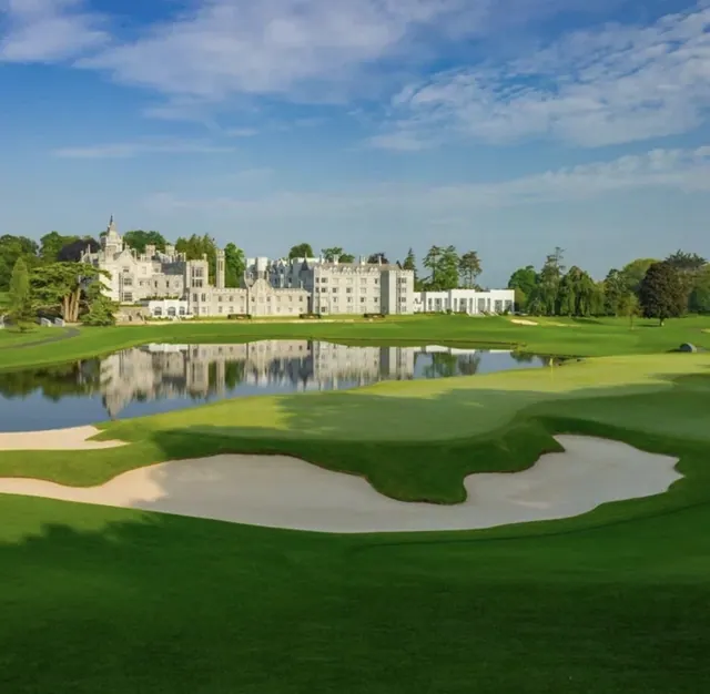 Adare Manor hotel reflected in the lake behind a large white sand bunker and green on the Adare Manor championship golf course, County Limerick, Ireland
