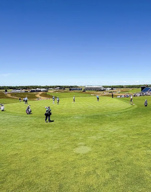 US Open practice round with players walking a fairway and a USA-flag Callaway caddie bag in the foreground