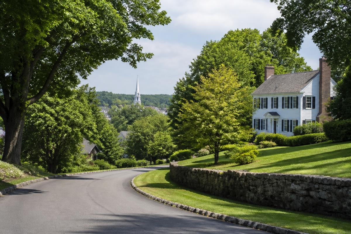 Leafy Westchester County residential road with stone walls and traditional houses in summer
